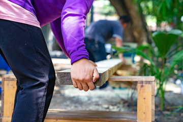worker scrubs the big long wood plate with polishing machine in the garden.
