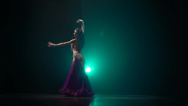 Brunette dances belly dancing. Smoke background