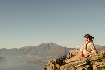 Woman Relax on a Mountain Top with Alpine Lake Maggiore in Background in Ticino, Switzerland.