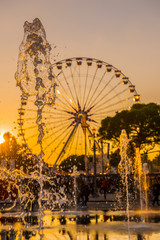 Water Fountain and Ferris Wheel in Sunset in Nice in Provence-Alpes-Côte d'Azur, France.