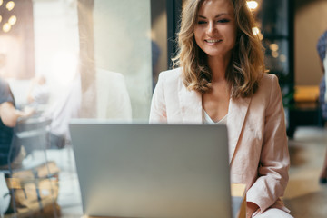 Happy manager having an online video call from abroad using modern laptop computer and free wifi in a cafe discussing plans and news with her colleagues and laughing