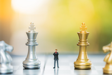 Business decision making concept. Miniature people : small businessman figure standing and walking on chessboard with chess pieces