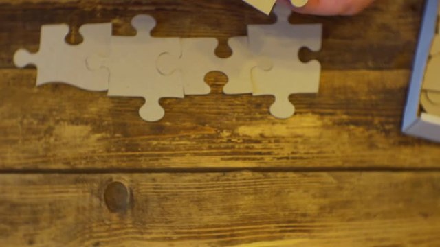 Hands folding puzzles on a wooden surface.top view