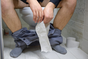 Man has stomach trouble, sitting on toilet bowl and has diarrhea or constipation or hemorrhoids. A...