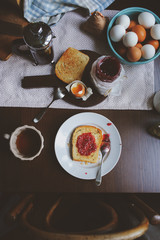 country cottage kitchen with breakfast on wooden table. Toast with jam, farm eggs and coffee