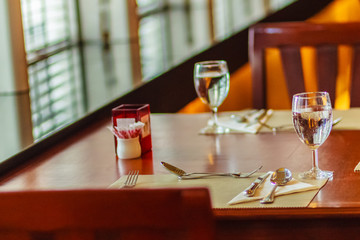 Glasses, spoon, frog, knife, napkin and plates on table setting for meeting and celebrating decoration.