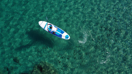 Aerial drone bird's eye view of 2 men exercising sup board in turquoise tropical clear waters