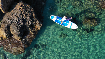 Aerial drone bird's eye view of 2 men exercising sup board in turquoise tropical clear waters