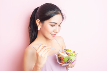 Beautiful Healthy young woman eating salad  on pink  background