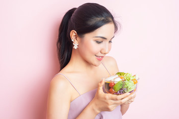 Beautiful Healthy young woman eating salad  on pink  background