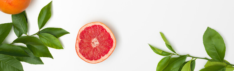 fresh, juicy grapefruit with green twigs lying on a white background