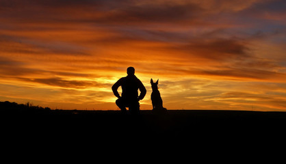 Fototapeta na wymiar The man and the dog on the background of the unlikely sunset