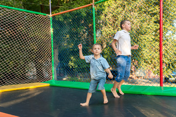 Two boys jump on the trampoline and cheerfully spend time