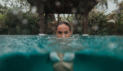 Beautiful woman having a bath in the swimming pool while it s raining