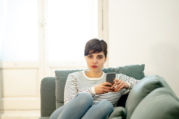 Young beautiful woman on mobile phone chatting on the internet while relaxing at home