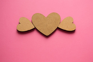 Light wooden heart with wings on pink background with copy space. Spring composition flat lay from top view.
