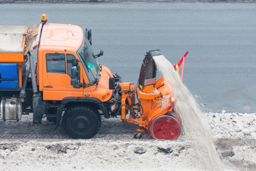 Machinery snowplough cleaning highway by removing cleans snow swinging on the side of the road
