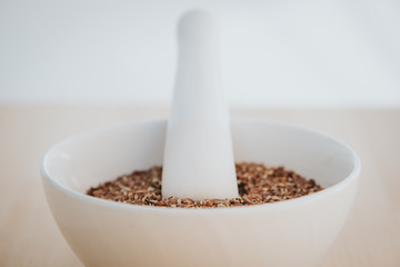 Leinsamen geschrotet in einer weißen Schüssel mit Mörser auf Holz Hintergrund