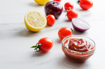 Closeup of full bowl with fresh organic homemade ketchup on white table in the kitchen