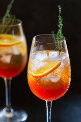 Aperol Stpritz, alcoholic cocktail with ice cubes and slices of orange, decorated with rosemary . Classic Italian aperitif beverage, prepared with prosecco some bitter liqueur and soda water.