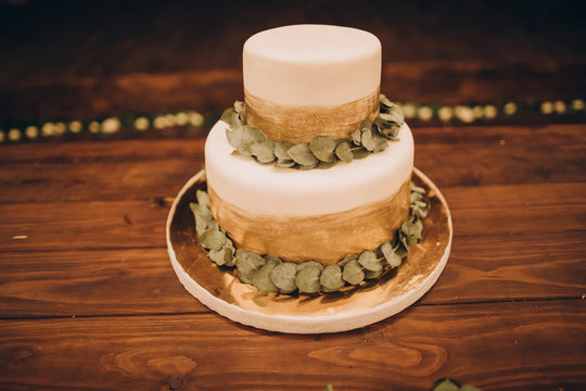 on a wooden table is a cake decorated with green leaves and cream