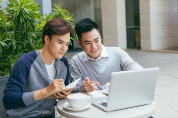 Business people looking at document and discussing while at cafe. Two businessmen working together on business report at coffee shop. - Image