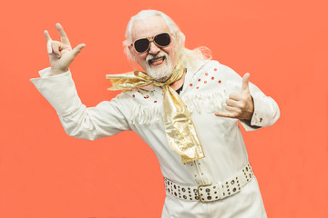 Old dressed up man pensioner who loves rock'n'roll, dancing and having fun on a living coral background - Concept of enjoying life at every age