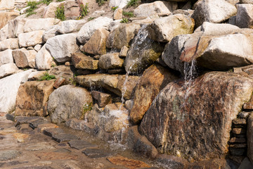 Texture of natural stone and flowing water. The source of water in the mountains