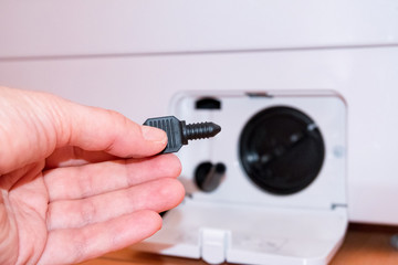 Washing machine with an open filter cover, hand holds part, key, part