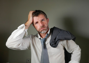 young attractive sad and worried businessman in lose tie and messy look feeling depressed and stressed in overwhelmed and frustrated face expression