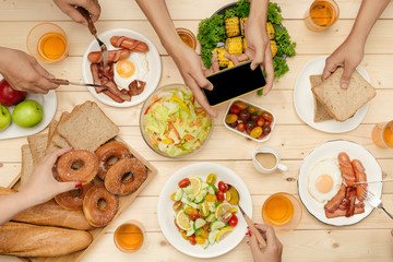 Enjoying dinner with friends.  Top view of group of people having dinner together while sitting at wooden table
