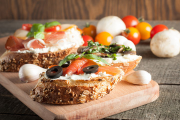 Italian tomato and cheese bruschetta. Tapas, antipasti with chopped vegetables, herbs and oil on grilled ciabatta and baguette bread.