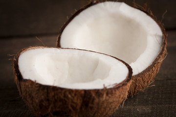 Fototapeta na wymiar Ripe half cut coconut on a wooden background. Coconut cream and oil.