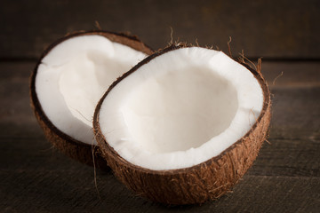 Ripe half cut coconut on a wooden background. Coconut cream and oil.
