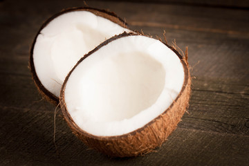 Ripe half cut coconut on a wooden background. Coconut cream and oil.