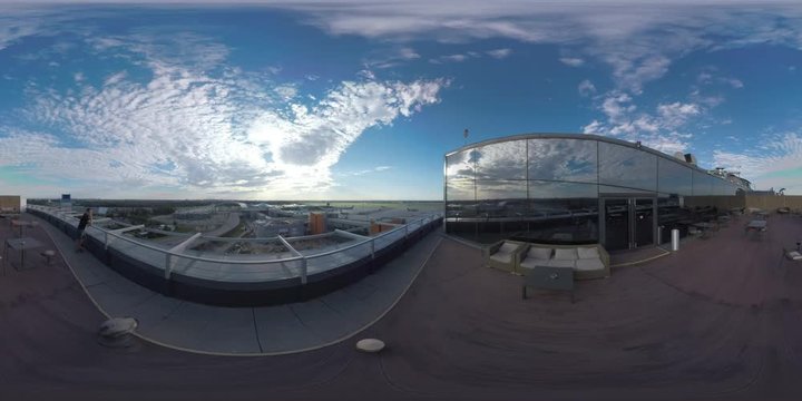 MOSCOW, RUSSIA - AUGUST 08, 2017: 360 VR video. Hotel rooftop with cafe and man (with model release) looking at road traffic and Sheremetyevo Airport with airplane taking off