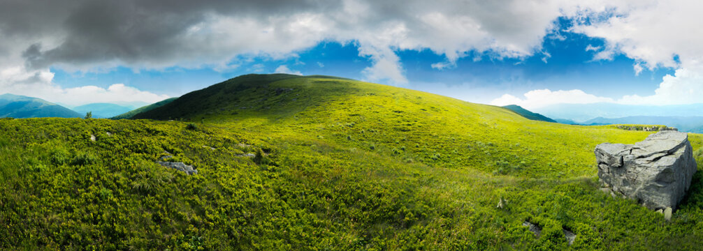 panorama with rock on the grassy hill in mountains. beautiful summer landscape. idyllic nature scenery. blue sky surrounded with clouds