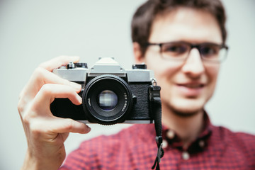 Fototapeta premium Young man is taking a picture with a vintage camera