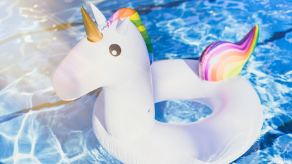 Inflatable colorful white unicorn at the swimming pool. Vacation time in the swim pool with plastic...