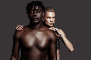 Fototapeta na wymiar Couple of modern young models posing near dark grey wall
