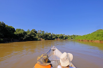 Boat with two unrecognizable tourists driving on the Aquidauana river in the brazilian Pantanal,...