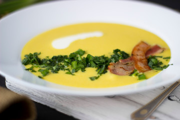 Pea soup with pieces of bacon, parsley and onion in a bowl on a dark background. Pea cream soup. Macro.