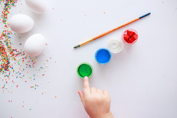 Baby painting eggs with brush and paints