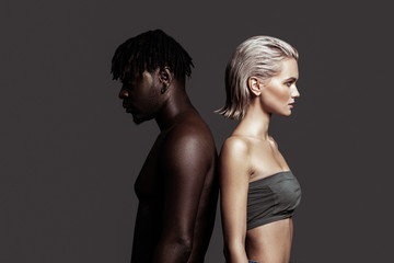 African-American man and white woman standing back to back