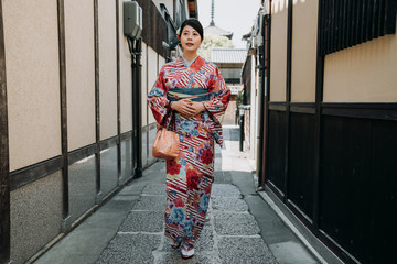 Fototapeta na wymiar full length of young japanese girl wearing traditional dress walking in path surrounding by old house in kyoto japan. local in kimono cloth going to yasaka pagoda temple daily routine lifestyle.