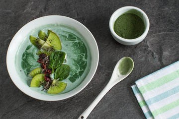 A green smoothie bowl with spinach,  spirulina powder, chia seeds, cranberries  and kiwi