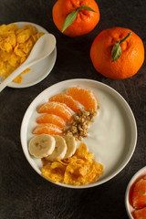 Smoothie bowl with tangerines,bananas,  granola and walnuts from above