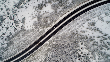 Aerial view of  winter asphalt highway or motorway road in countryside with cars and cargo logistic trucks in winter time