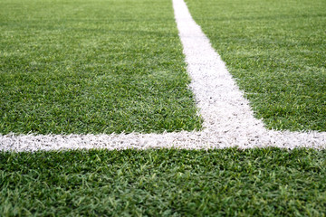 Artificial green grass with white stripe of soccer field