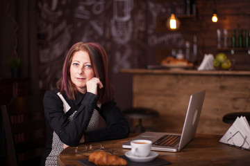 Potrait of adult woman using her laptop in restaurant